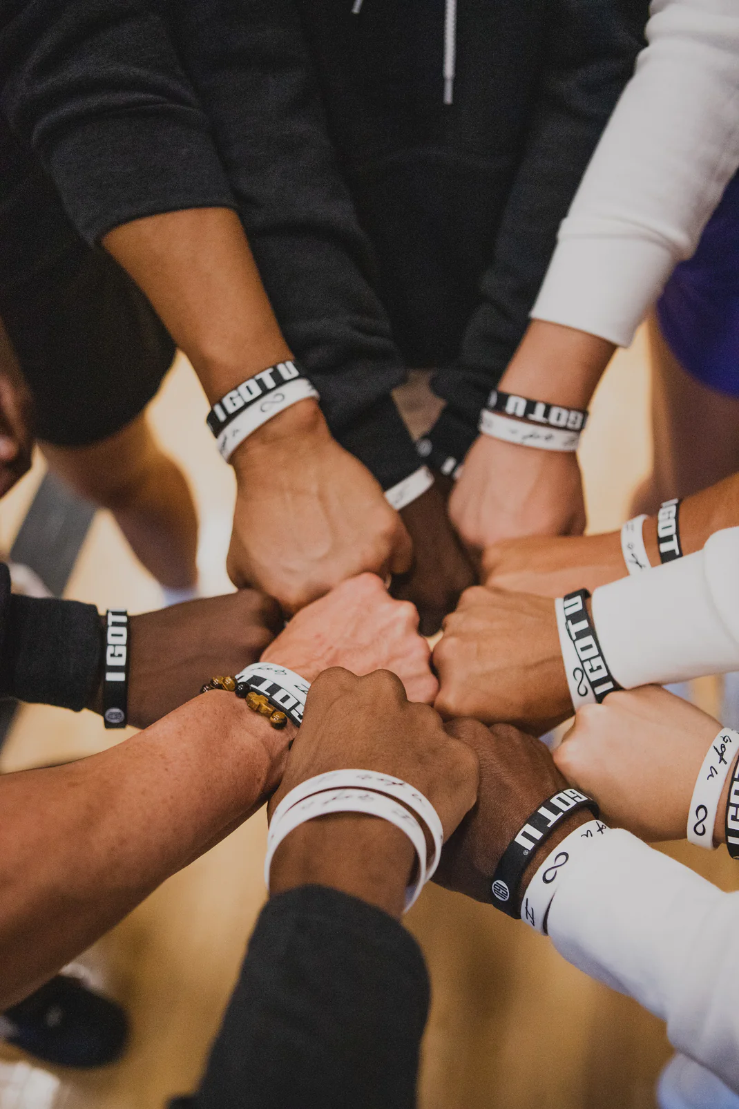 Hands joined in a circle, each wearing an IGOTU® wristband
